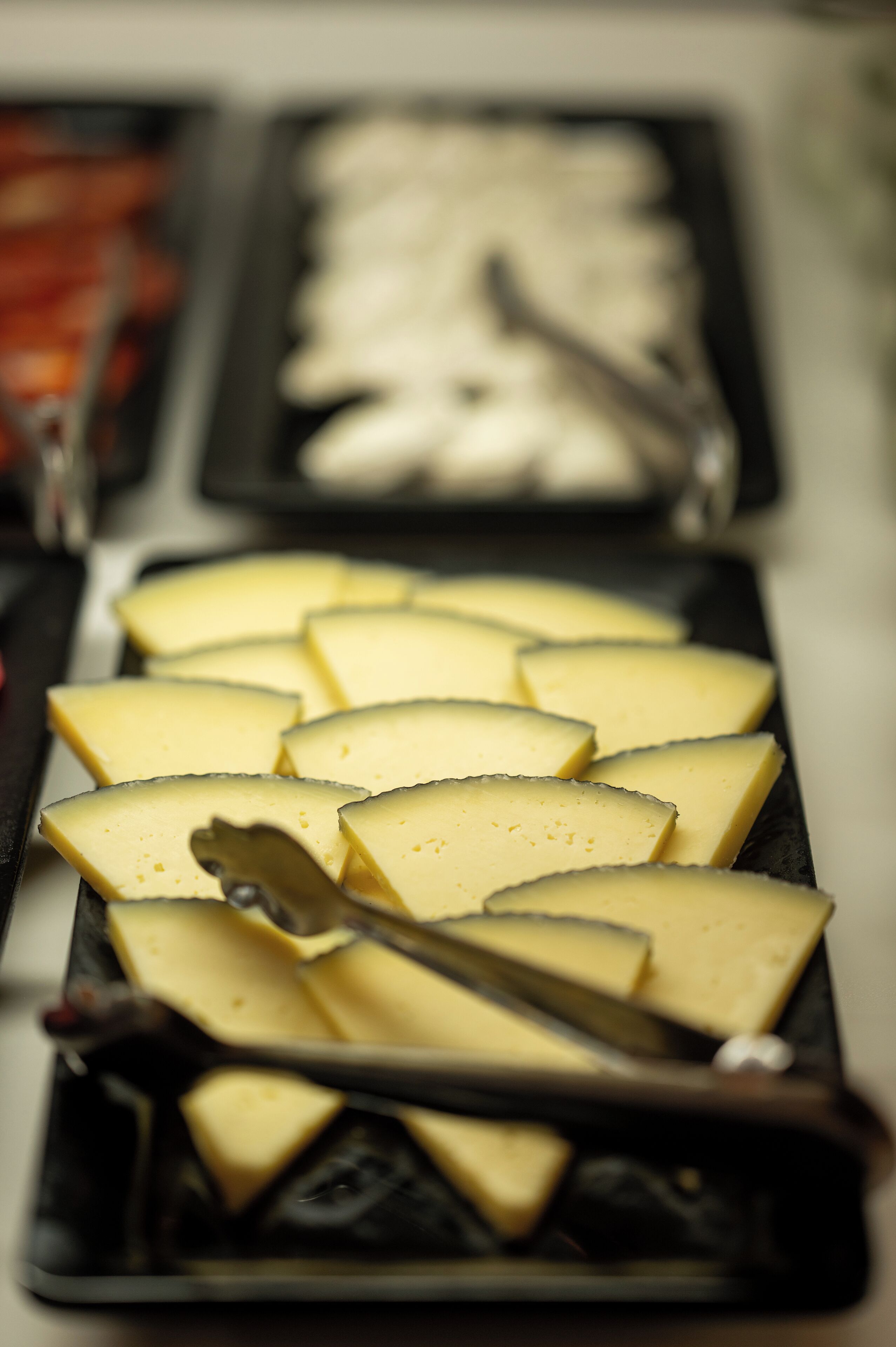 Una bandeja de rebanadas de queso con un cuchillo para queso.