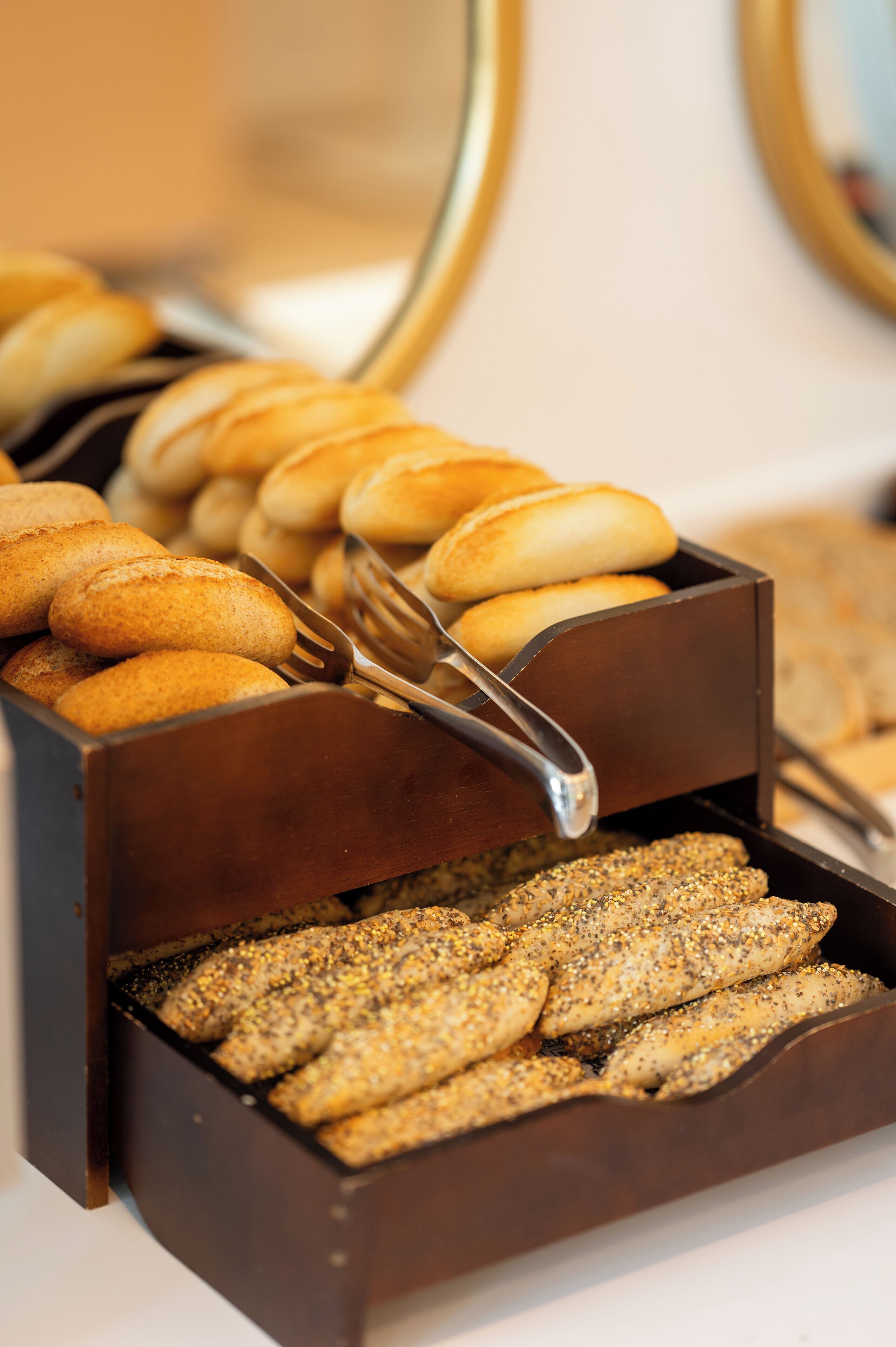 A buffet with various baked goods, including bread rolls and sesame seed bread.