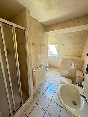 A bathroom with a shower, toilet, and sink.
