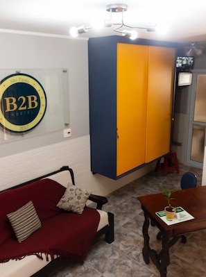 A room with a bed, a wardrobe, a desk, and a wall-mounted sign.
