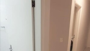 A hallway with white walls and a tiled floor, leading to a door with a small step. - Hostel B2B (São Paulo)