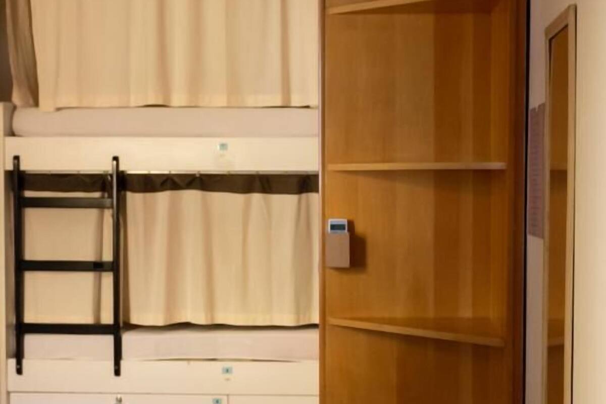 A bunk bed room with a wooden wardrobe and a small desk.