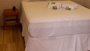 A neatly made bed with pillows and a small bedside table with a plant. - Hostel B2B (São Paulo)