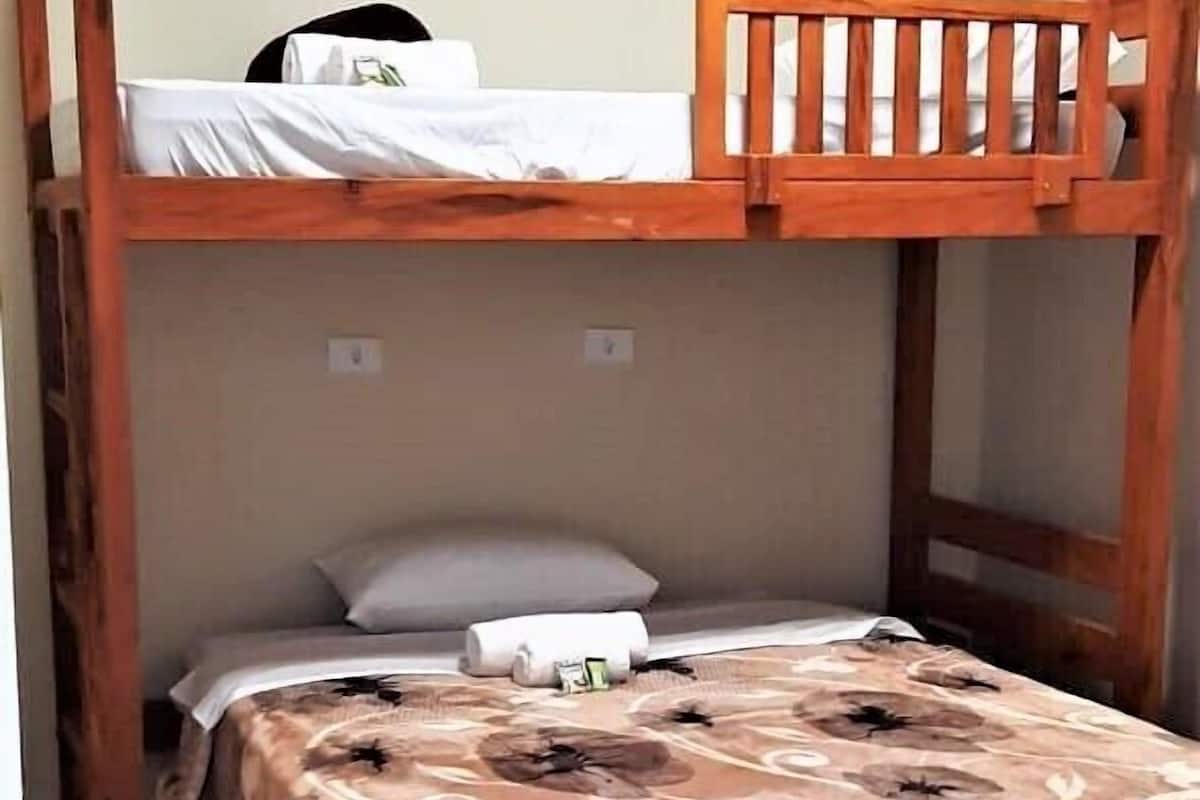 A bunk bed with a wooden frame, a patterned bedspread, and a pillow.