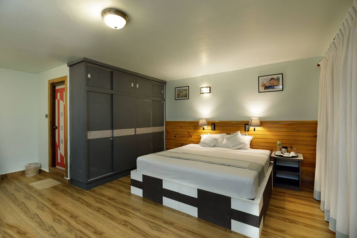 A bedroom with a bed, wardrobe, bedside table, and a picture on the wall.