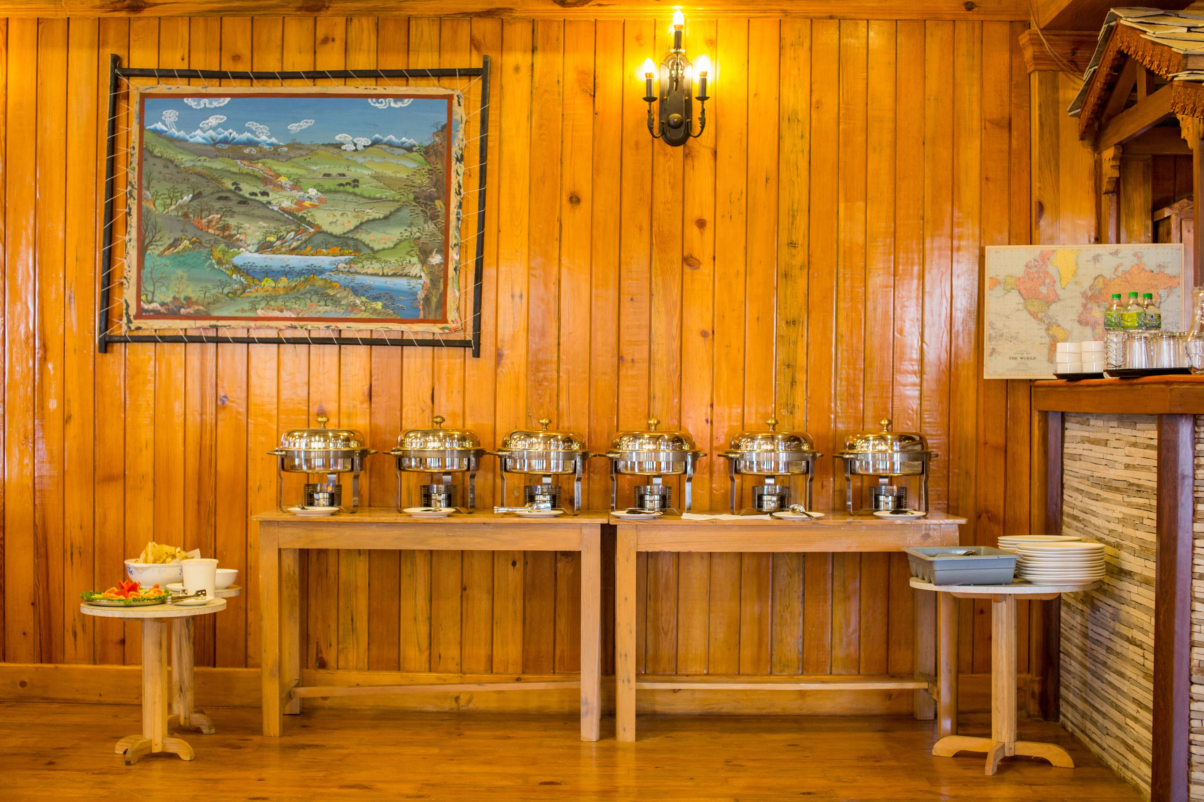 A wooden-paneled room with a buffet table, a painting, and a map on the wall.