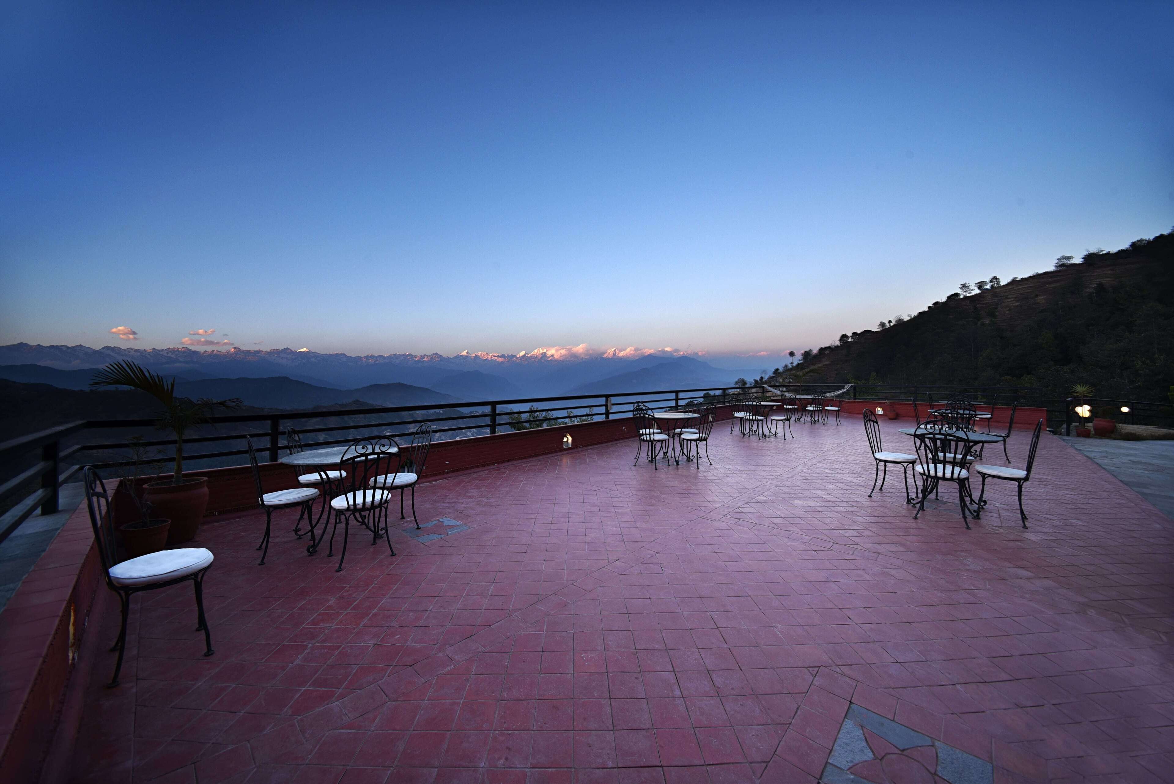 Une terrasse extérieure, agréée de tables et de chaises, qui offre une vue sur un paysage montagneux.