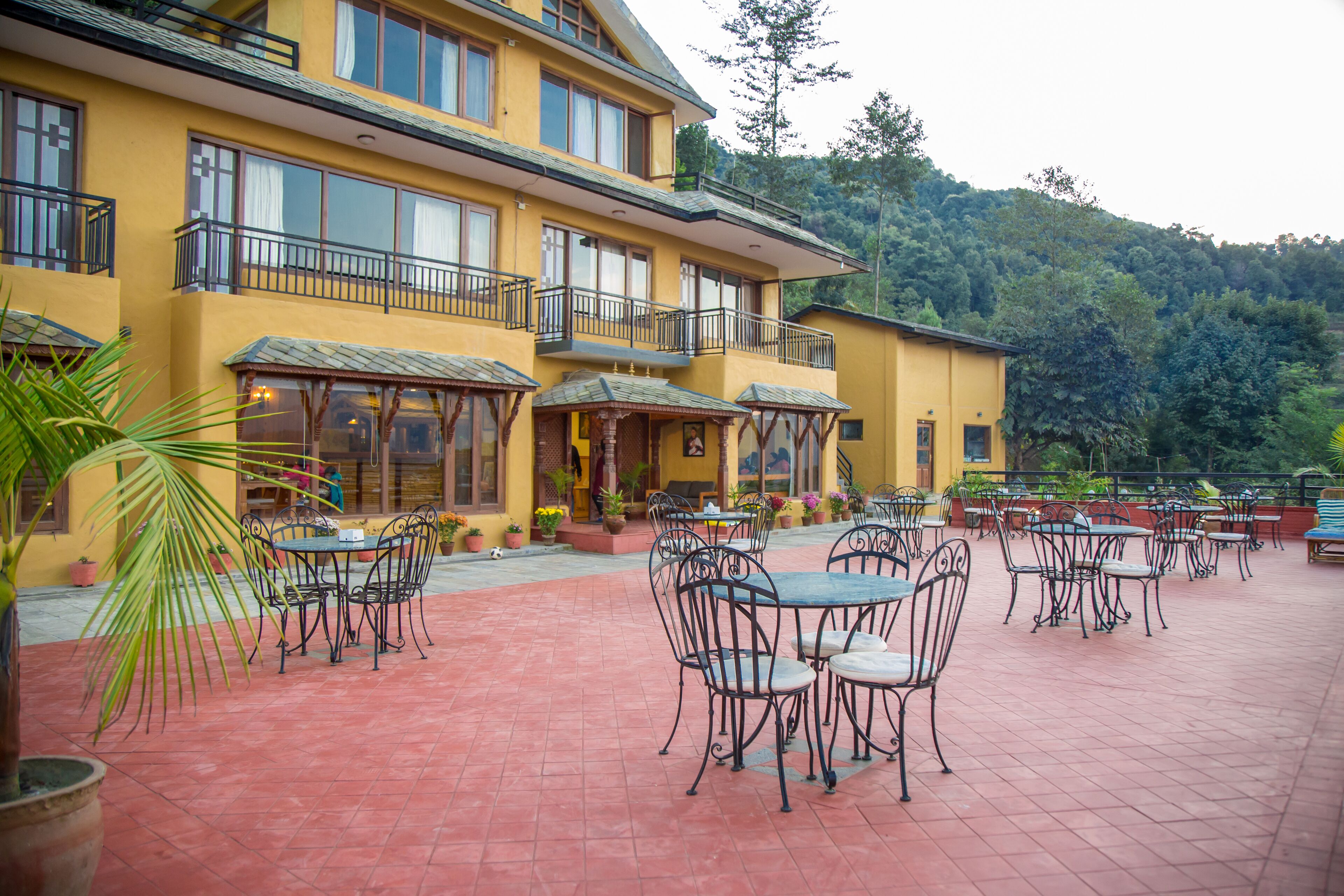 A yellow building with outdoor seating and a staircase leading to a balcony.