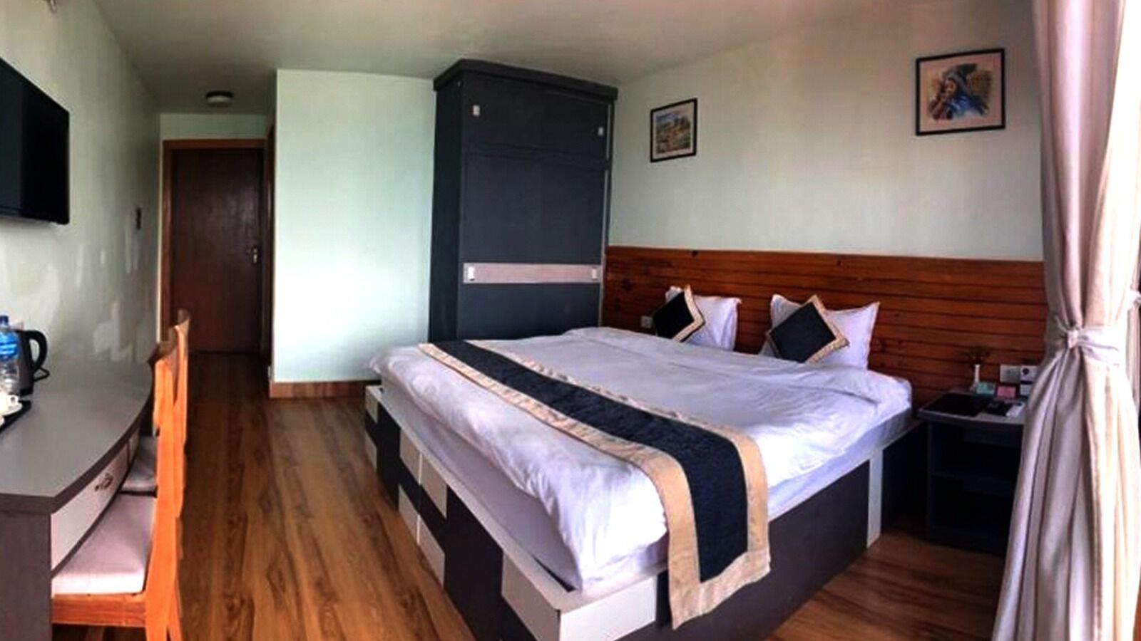 Un dormitorio con una cama grande, cabecera de madera, un escritorio con silla y una mesita de noche con lámpara.