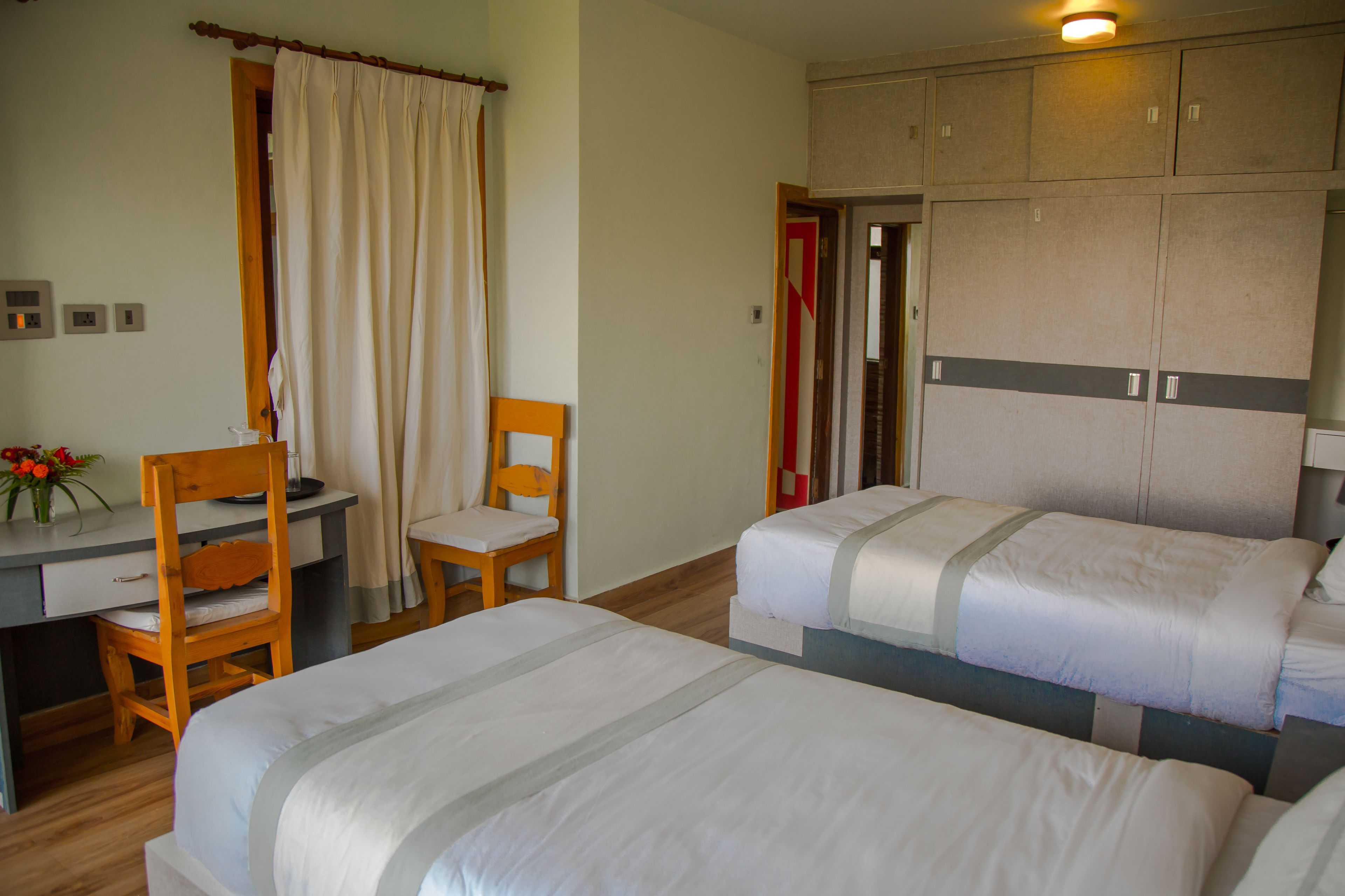 Una habitación de hotel con dos camas, un escritorio, una silla y un armario.