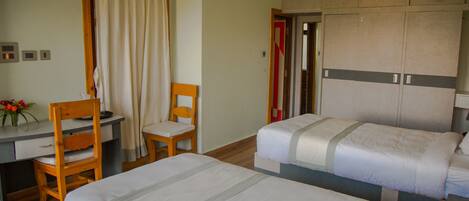 Una habitación de hotel con dos camas, un escritorio, una silla y un armario.