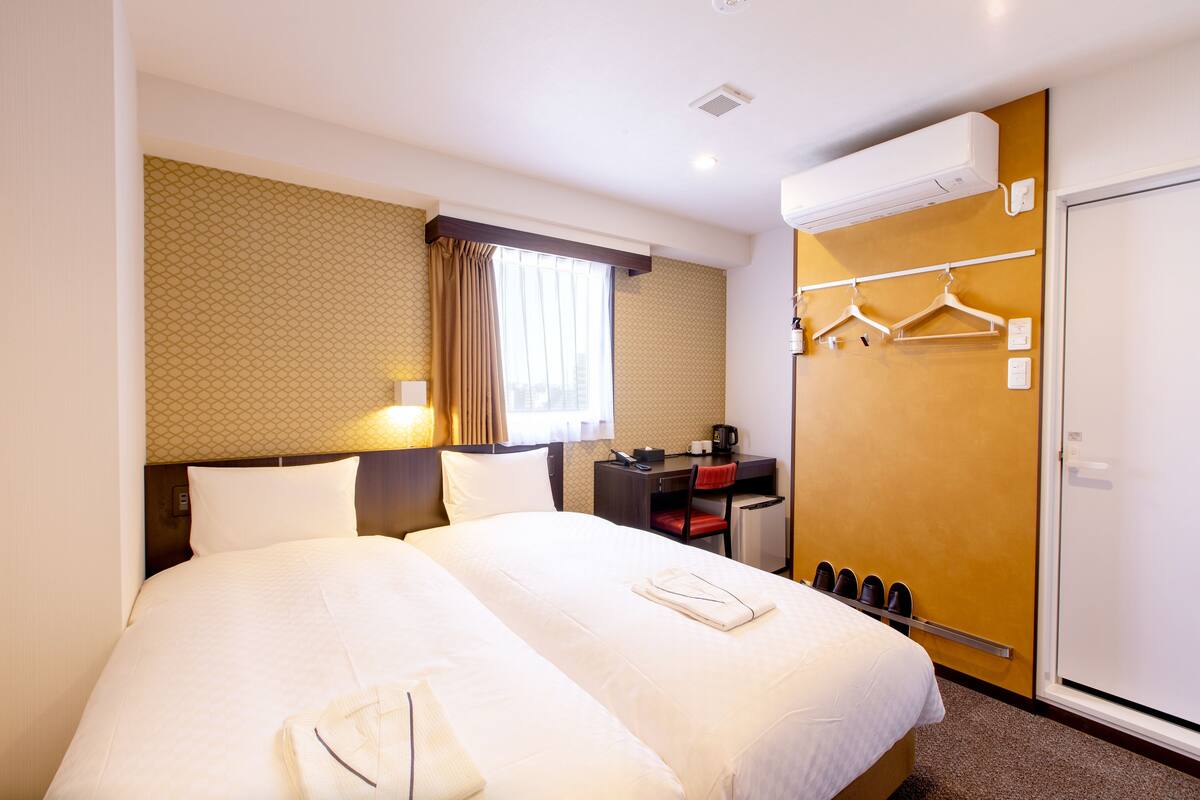 Une chambre d’hôtel avec un grand lit, un bureau avec une chaise, un porte-manteau et une armoire.