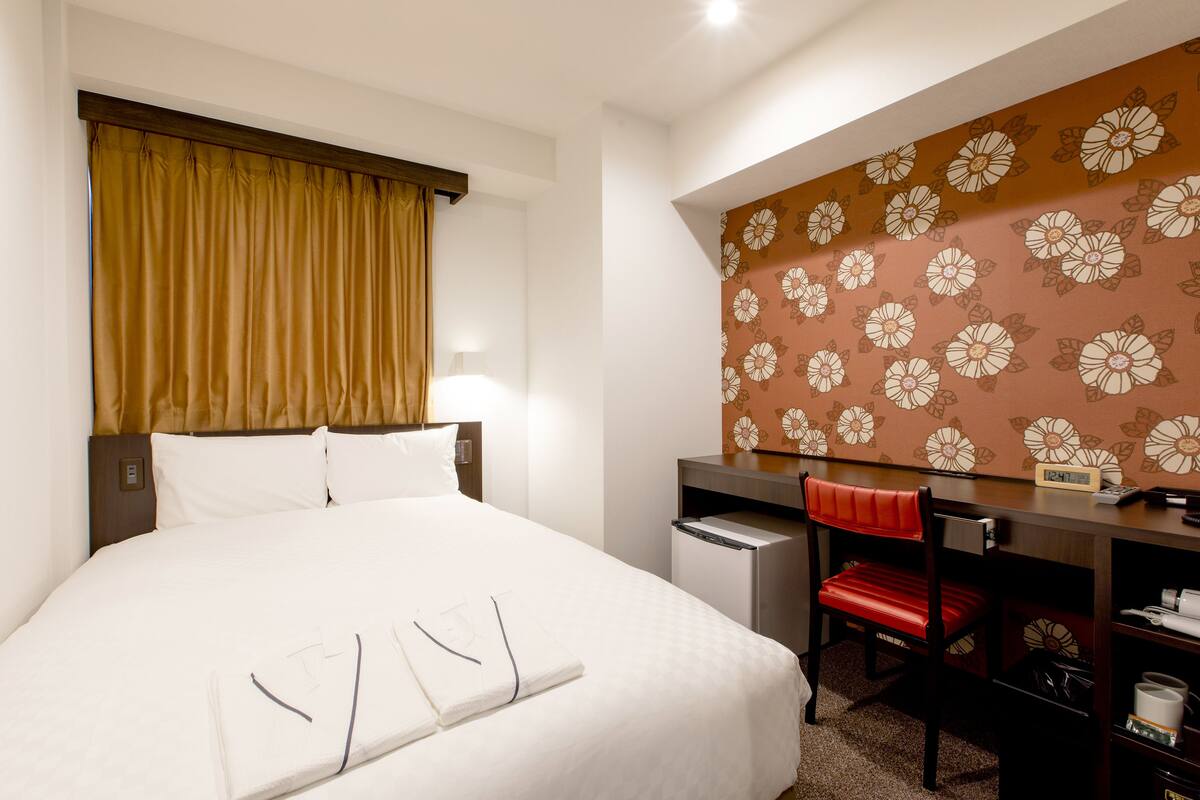 Une chambre d’hôtel comprenant un lit, un bureau, une chaise et une armoire.