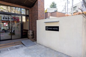 A hotel entrance with a glass door, a sign reading 'KO KOKO HOTEL,' and a wooden barrel outside. - KOKO HOTEL Akabane Station (Tokyo)