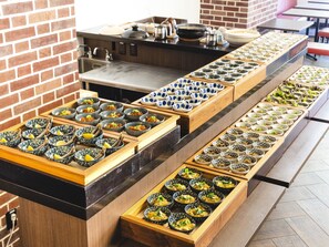 A buffet with various dishes arranged in trays. - KOKO HOTEL Akabane Station (Tokyo)
