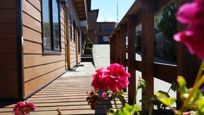 Una terraza de madera con una hilera de edificios a un lado y una valla de madera al otro.