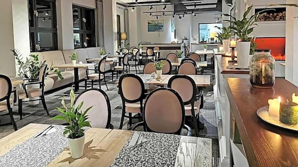 A modern dining area with multiple tables and chairs, a bar area with a counter, and potted plants. - Hotel Nafta Krosno (Krosno)