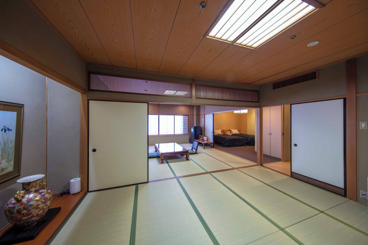 Una habitación japonesa tradicional con suelo de tatami, una mesa baja de tatami, un sofá y puertas correderas.
