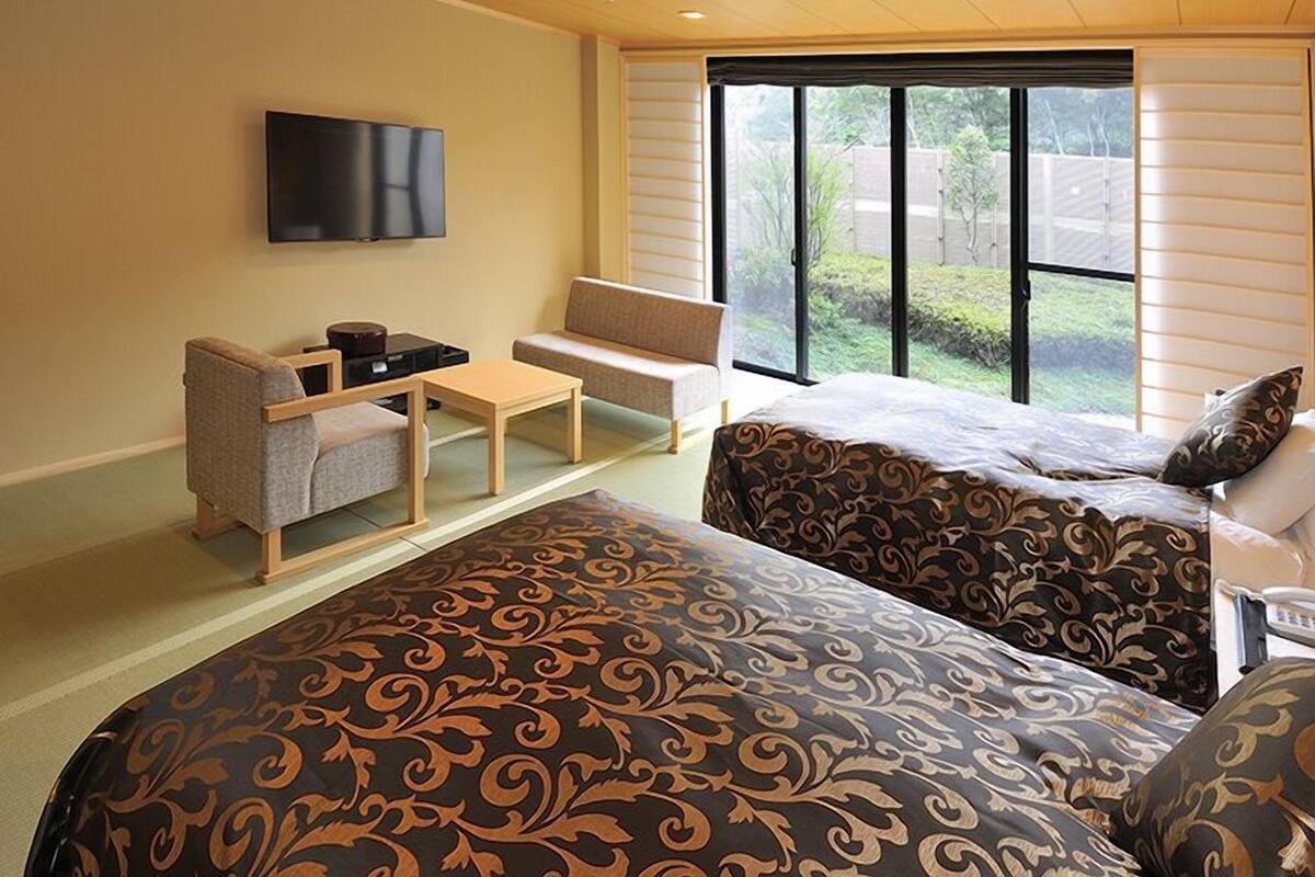 Habitación de hotel con dos camas, un sofá, un televisor y una mesita.