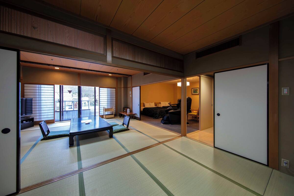 Una habitación japonesa tradicional con suelo de tatami, una mesa baja y puertas correderas.