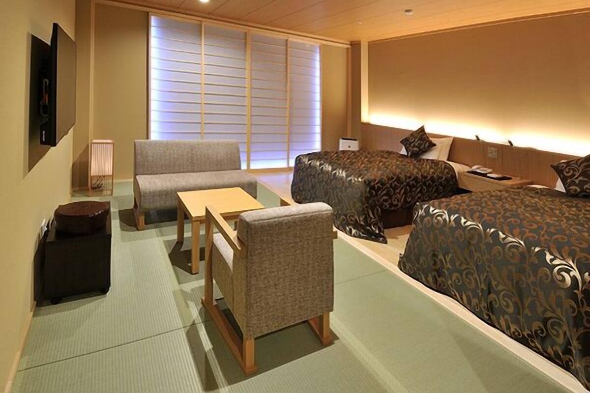 Habitación de hotel con sofá, dos camas, una mesita y una lámpara.