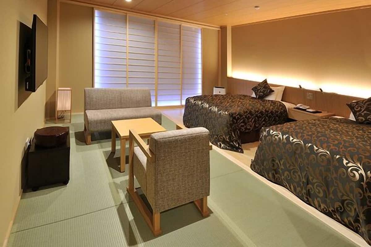 Habitación de hotel con sofá, dos camas, una mesita y una lámpara.