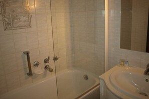 A bathroom with a bathtub, a shower, and a sink.