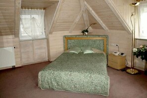 A bedroom with a bed, a bedside table, a lamp, and a window with curtains. - Hotel Villa Sulmana (Neckarsulm)