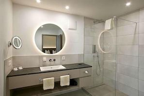 Een moderne badkamer met een ronde spiegel, een wastafel en een douchecabine met glazen wanden.