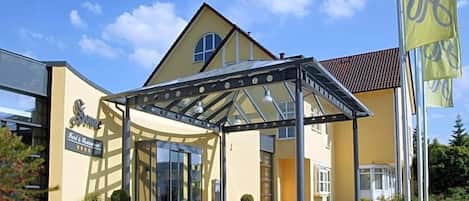 A hotel entrance with a covered walkway, a glass door, and a sign indicating a restaurant.