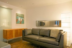 Una sala de estar moderna con un sofá de cuero, una consola de madera y un espejo grande.
