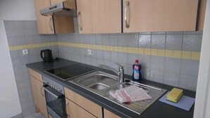 A kitchen with a stove, sink, and a kettle. - Wo der Hahn Kräht (Flein)