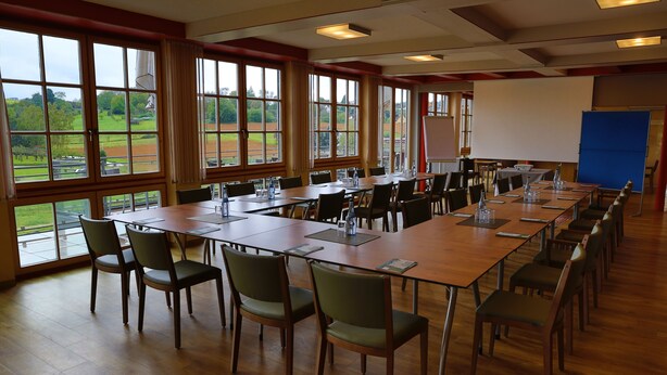 A conference room with long tables, chairs, and a projector screen. - Wo der Hahn Kräht (Flein)