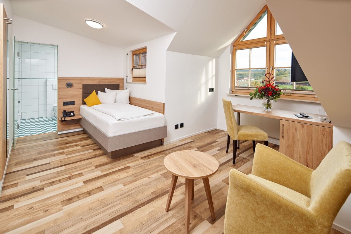 Habitación de hotel moderna con cama, escritorio, silla y vista al exterior.