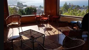 En balkon med fletmøbler, et bord og udsigt over havet og bybilledet.