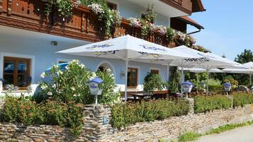 Ein traditionelles Gebäude mit Außenbestuhlung und Blumenkästen am Balkon.