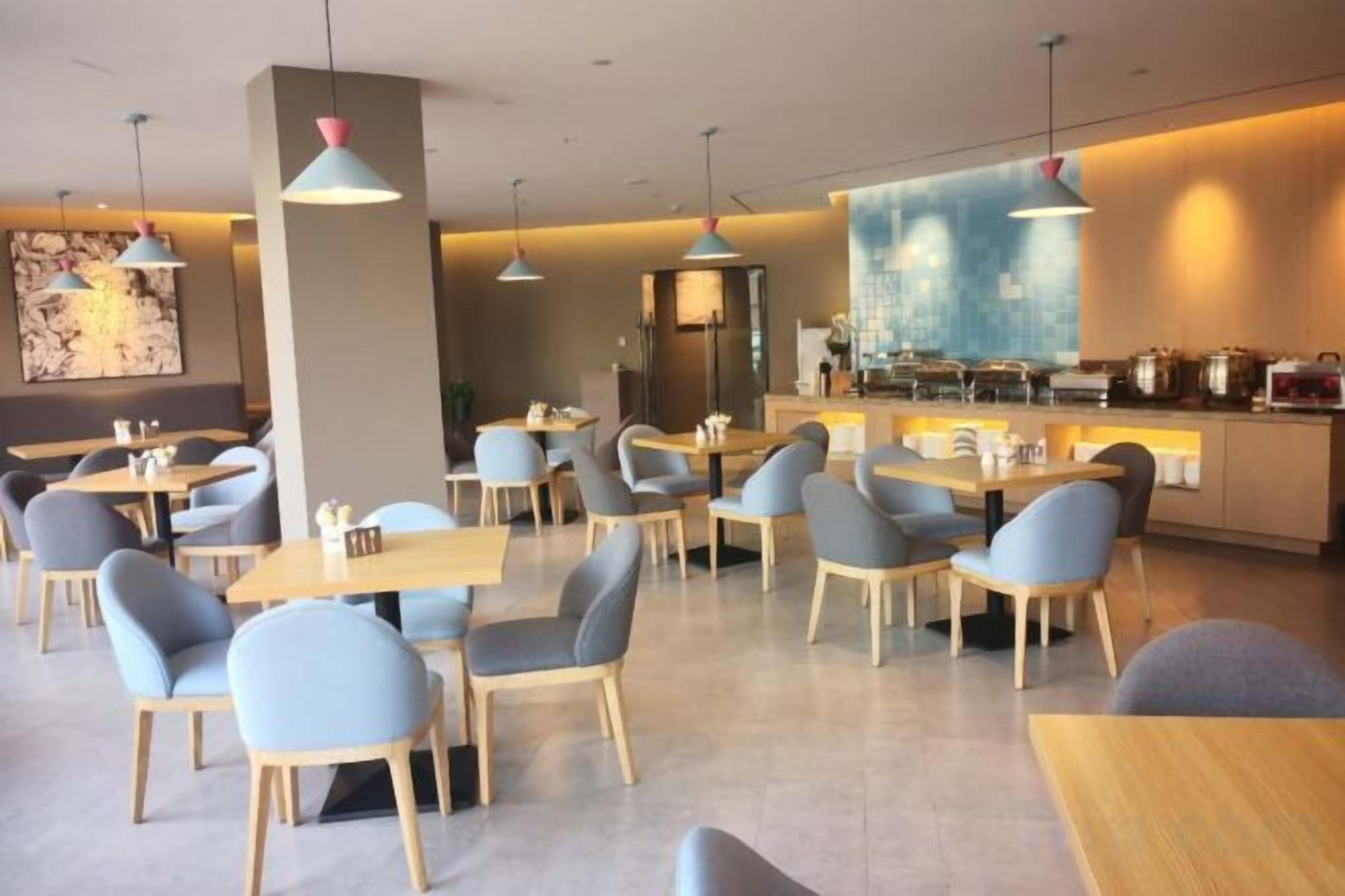 Un restaurante moderno con varias mesas y sillas, una zona de bar y un cuadro abstracto grande en la pared.