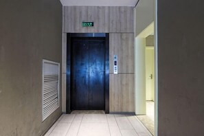 An elevator with a digital display, a wall-mounted control panel, and a door with a metallic handle. - Homeinn · neo (Qingdao Chengyang Zhengyang Middle Road Wanxianghui) (Qingdao)