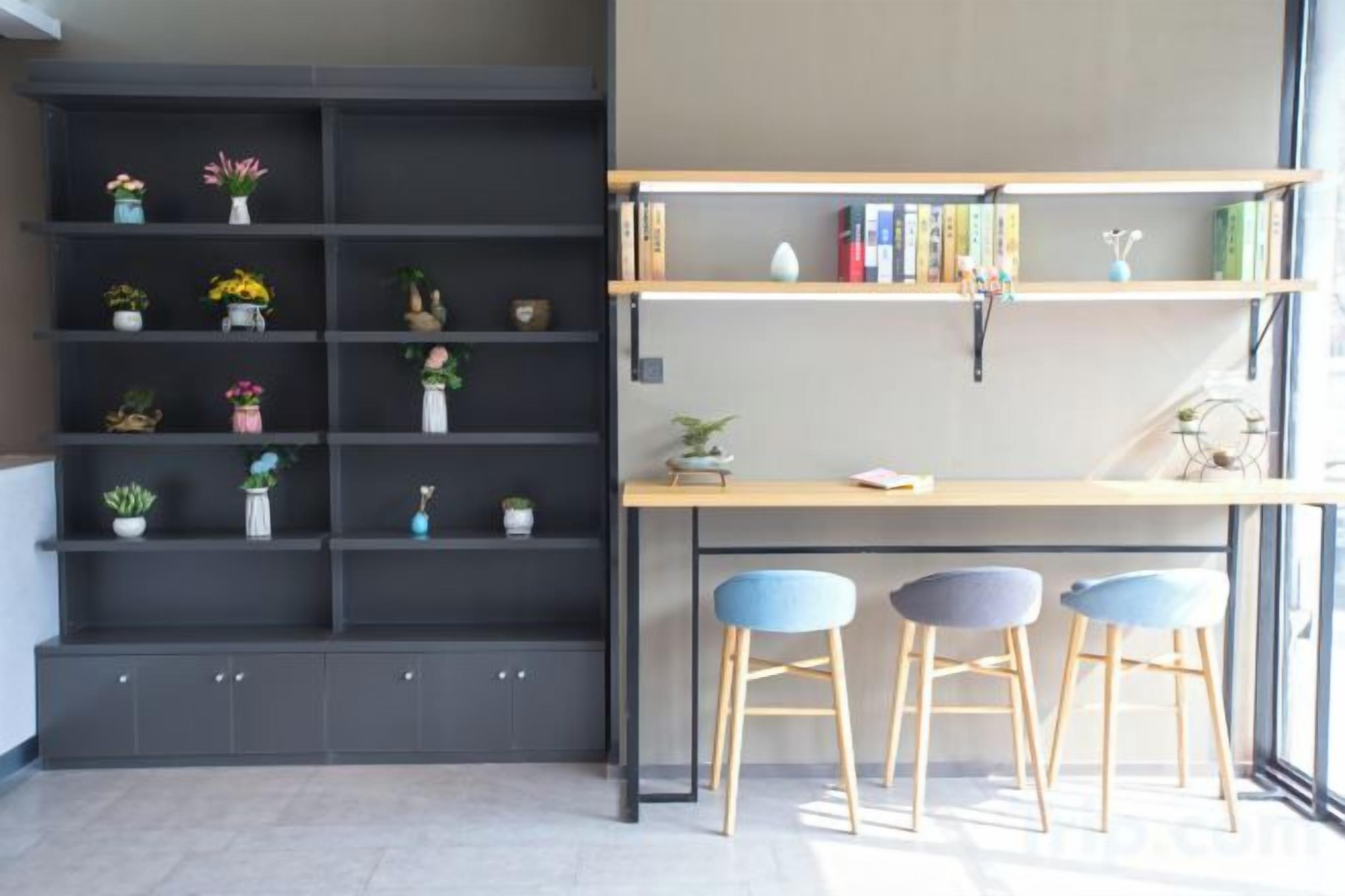 Un espacio de trabajo con un escritorio, dos sillas y una estantería con plantas y libros.