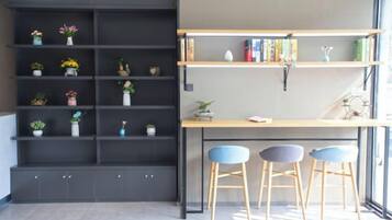 Un espacio de trabajo con un escritorio, dos sillas y una estantería con plantas y libros.