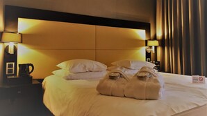 Ein Hotelzimmer mit einem großen Bett, zwei Nachttischlampen, einer Kaffeemaschine und einem Schild für kostenloses WLAN.
