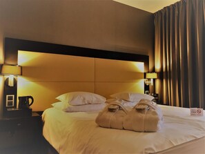 Ein Hotelzimmer mit einem großen Bett, zwei Nachttischlampen, einer Kaffeemaschine und einem Schild für kostenloses WLAN.