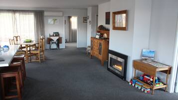 Una sala de estar con chimenea, una mesa de comedor con sillas, un aparador de madera y un televisor sobre un mueble.