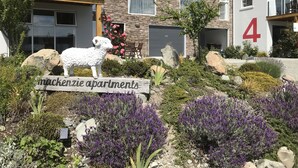 Ein modernes Apartmenthaus mit Stein-Fassade, Nummer 4, und einer dekorativen Schaf-Statue in der Grünanlage.