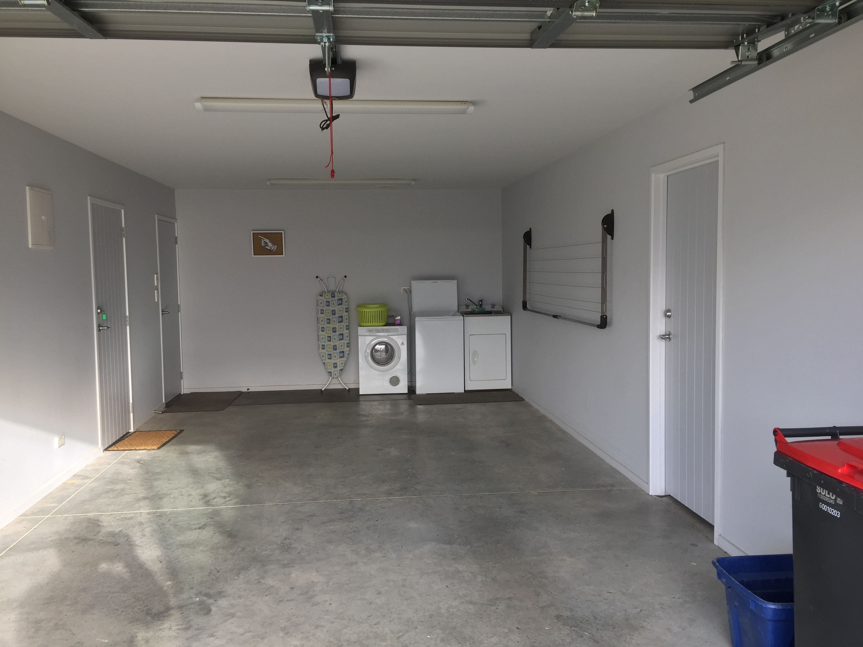 Un garage con lavatrice, asciugatrice e un asse da stiro.