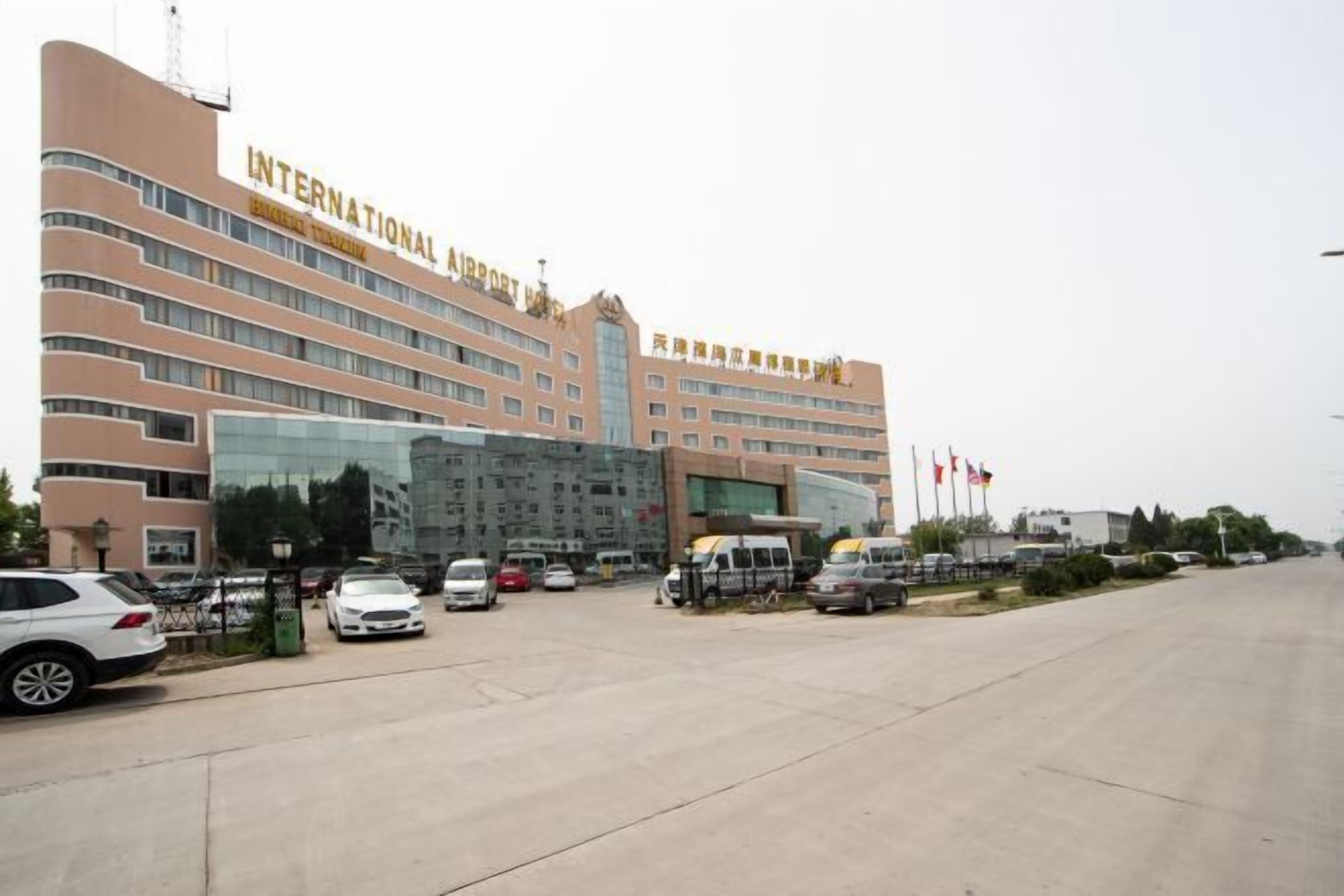 An INTERNATIONAL AIRPORT HOTEL with multiple floors, a parking area, and several flags.
