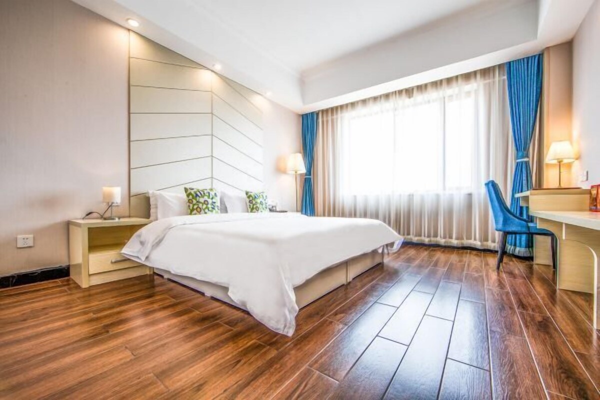Una habitación de hotel moderna con una cama grande, un escritorio y una silla.