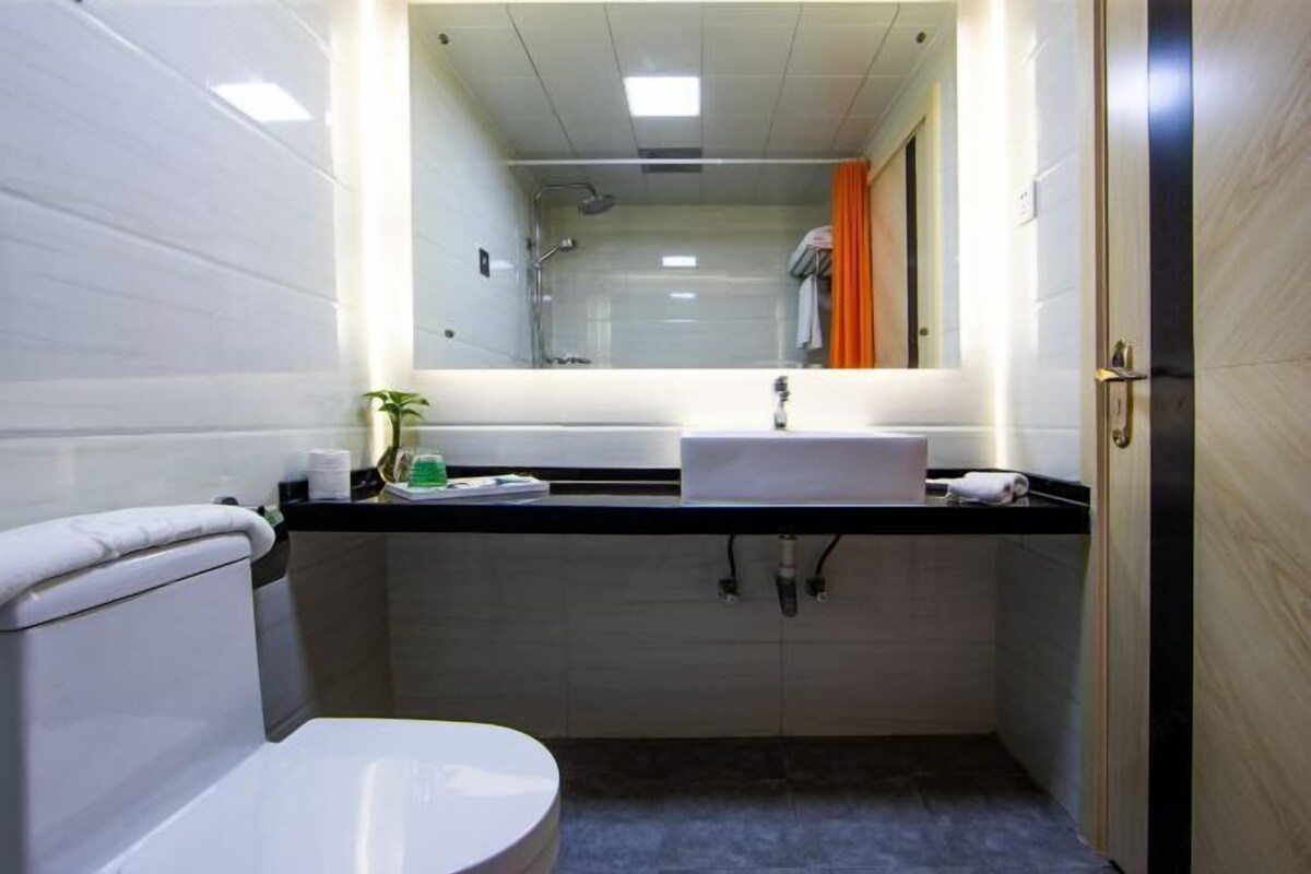 A compact bathroom with a toilet, sink, and shower.