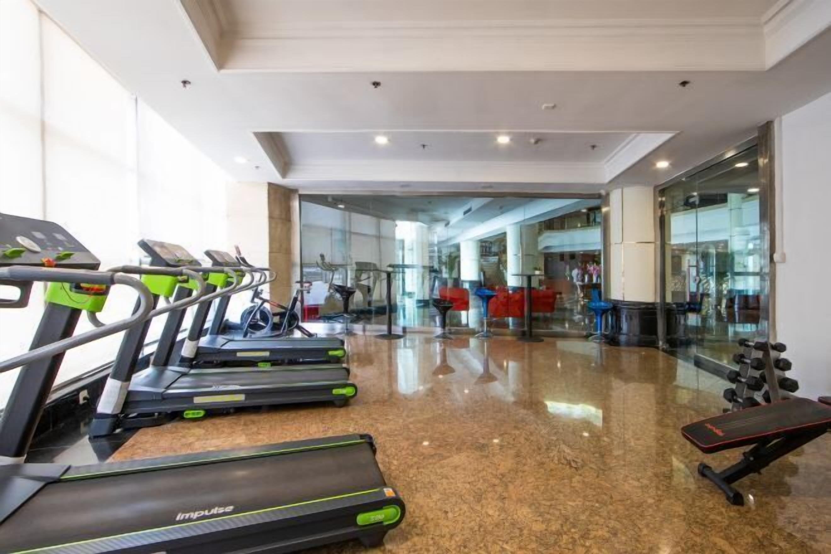 A gym with treadmills, a bench, and weights.