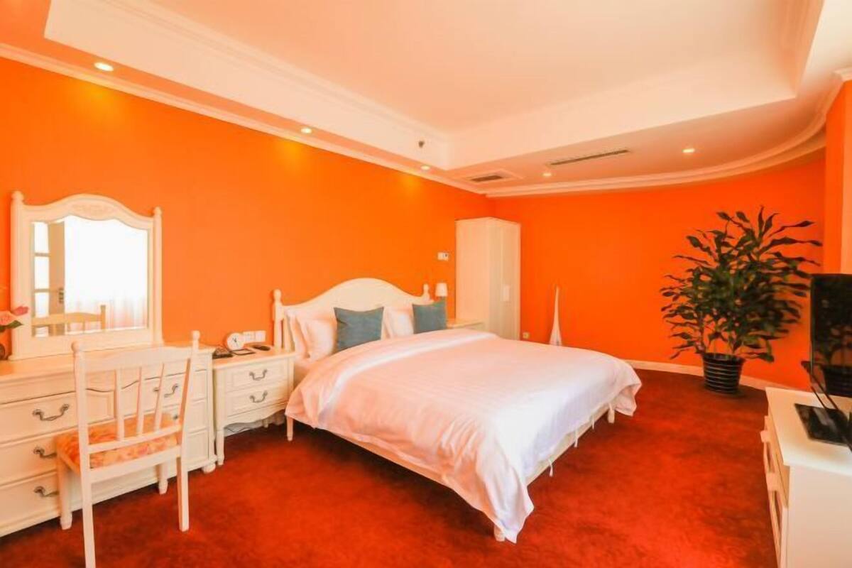 Ein Schlafzimmer mit Bett, Schminktisch, Spiegel und einer Zimmerpflanze.